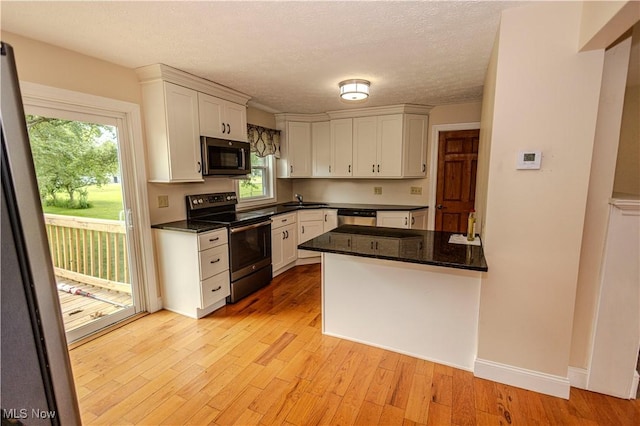 9306 Beech St, Louisville, OH 44641 - kitchen with appliances with stainless steel finishes, white cabinets, light wood-style flooring, a textured ceiling, and a peninsula