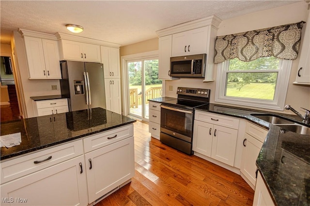 9306 Beech St, Louisville, OH 44641 - kitchen with stainless steel appliances, white cabinetry, light wood-style floors, and dark stone countertops