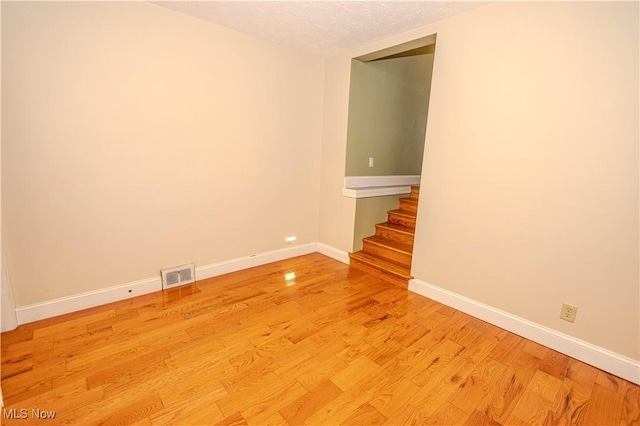 9306 Beech St, Louisville, OH 44641 - spare room with stairway, light wood finished floors, and a textured ceiling