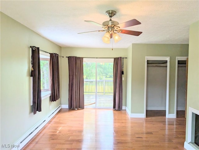 9306 Beech St, Louisville, OH 44641 - unfurnished bedroom featuring baseboard heating, access to exterior, light wood-style flooring, a ceiling fan, and a textured ceiling
