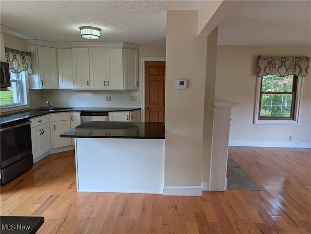 9306 Beech St, Louisville, OH 44641 - kitchen with appliances with stainless steel finishes, light wood-style floors, dark countertops, white cabinetry, and a textured ceiling