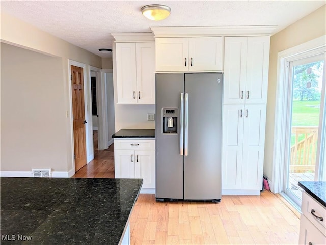 9306 Beech St, Louisville, OH 44641 - kitchen with stainless steel fridge, light wood-type flooring, white cabinetry, dark stone countertops, and a textured ceiling