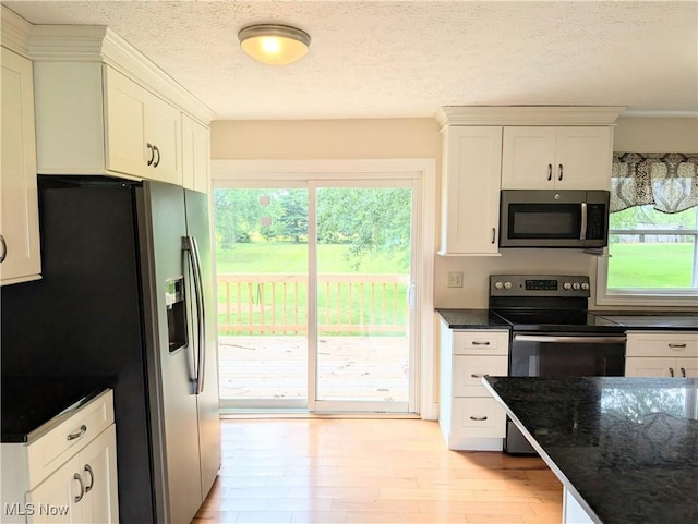 9306 Beech St, Louisville, OH 44641 - kitchen featuring appliances with stainless steel finishes, healthy amount of natural light, white cabinets, light wood-style floors, and a textured ceiling