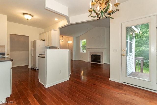 583 Mock Orange Cir, Chagrin Falls, OH 44023 - kitchen featuring white refrigerator with ice dispenser, a chandelier, dark wood-style flooring, a tile fireplace, and white cabinetry
