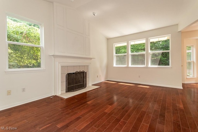 583 Mock Orange Cir, Chagrin Falls, OH 44023 - unfurnished living room featuring a tiled fireplace, plenty of natural light, wood finished floors, and vaulted ceiling