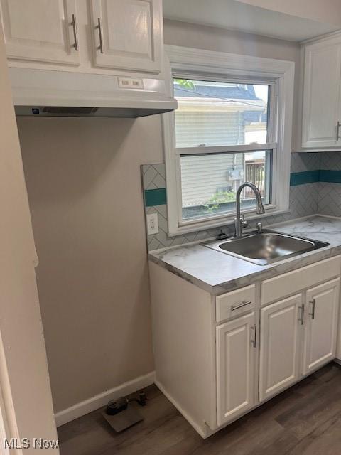 1700 Malasia Rd, Akron, OH 44305 - kitchen with under cabinet range hood, white cabinets, dark wood-style floors, decorative backsplash, and plenty of natural light