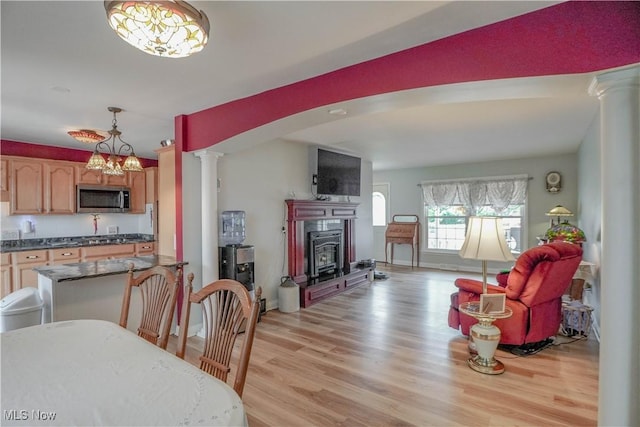 2077 Daniels Ave, Akron, OH 44312 - dining room with decorative columns, light wood-style floors, a glass covered fireplace, and a chandelier