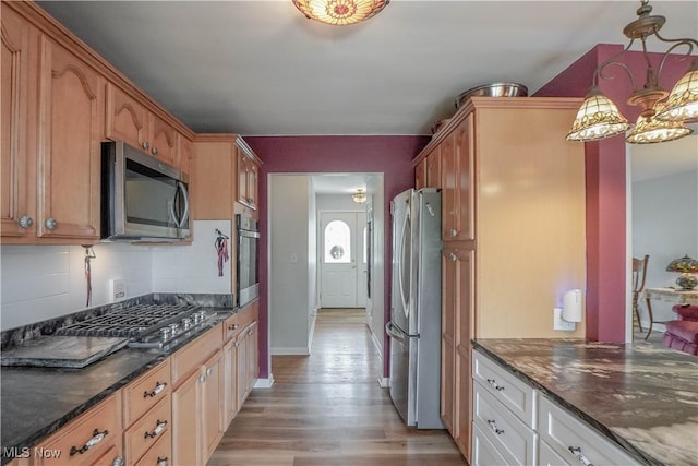 2077 Daniels Ave, Akron, OH 44312 - kitchen featuring appliances with stainless steel finishes, light wood-style flooring, backsplash, and dark stone countertops