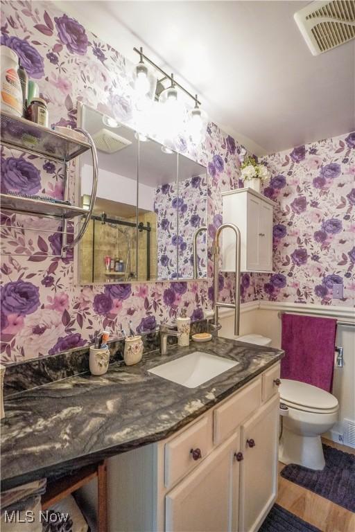 2077 Daniels Ave, Akron, OH 44312 - full bath featuring wallpapered walls, a wainscoted wall, vanity, wood finished floors, and a shower
