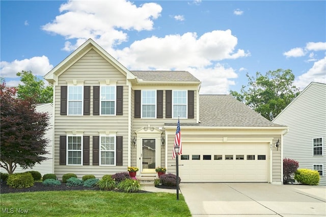 colonial home featuring concrete driveway, a front lawn, a garage, and a shingled roof