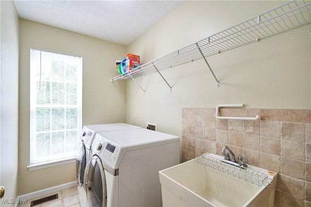 laundry area with washing machine and clothes dryer and tile walls