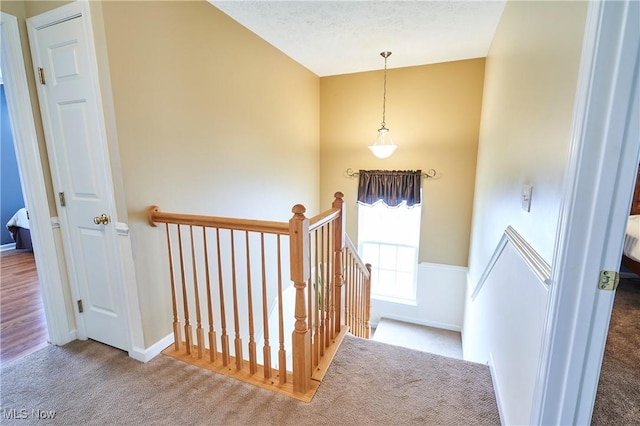 hallway with an upstairs landing and carpet