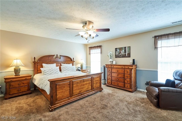 carpeted bedroom featuring ceiling fan and a textured ceiling