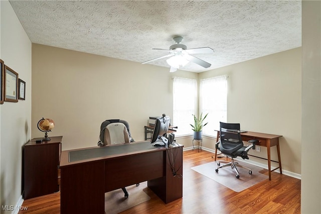 home office featuring a ceiling fan, wood finished floors, and a textured ceiling