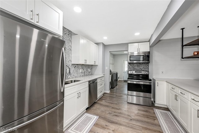 908 Dawnwood Dr, Parma, OH 44134 - kitchen featuring stainless steel appliances, decorative backsplash, light countertops, white cabinetry, and light wood-type flooring