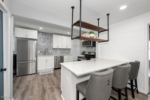908 Dawnwood Dr, Parma, OH 44134 - kitchen with appliances with stainless steel finishes, dark wood-style flooring, white cabinetry, backsplash, and recessed lighting