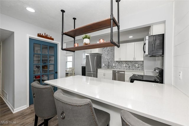 908 Dawnwood Dr, Parma, OH 44134 - kitchen featuring stainless steel appliances, dark wood finished floors, a peninsula, tasteful backsplash, and a breakfast bar area