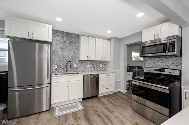 908 Dawnwood Dr, Parma, OH 44134 - kitchen with appliances with stainless steel finishes, separate washer and dryer, decorative backsplash, white cabinetry, and recessed lighting