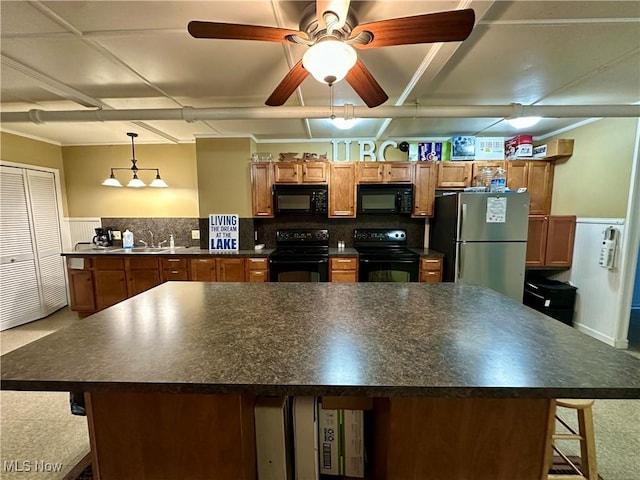 130 E 199th St, Euclid, OH 44119 - kitchen with black appliances, dark countertops, brown cabinetry, and wainscoting