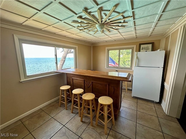 130 E 199th St, Euclid, OH 44119 - kitchen featuring freestanding refrigerator, crown molding, light tile patterned floors, and a kitchen bar