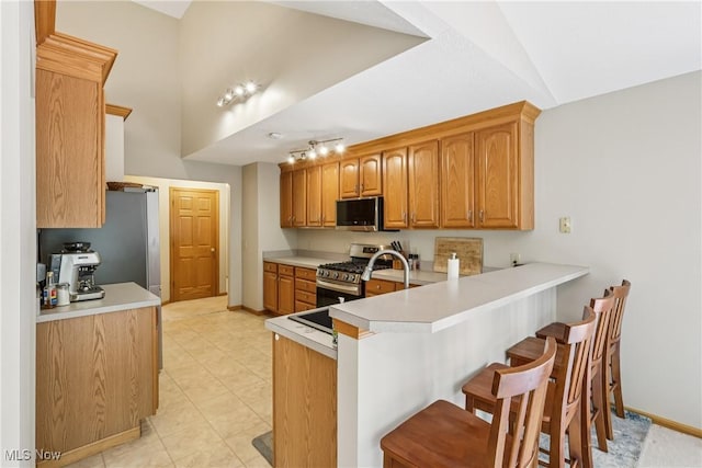 957 Devonwood Dr, Wadsworth, OH 44281 - kitchen with appliances with stainless steel finishes, a kitchen breakfast bar, a peninsula, brown cabinets, and light countertops