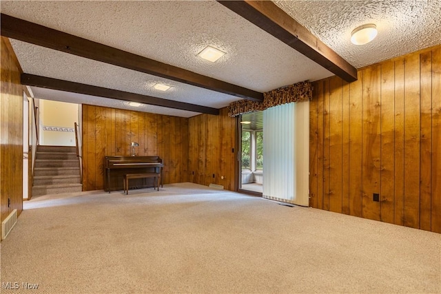 5200 Tanglewood Ave NE, Louisville, OH 44641 - unfurnished living room featuring a textured ceiling, wood walls, carpet flooring, beamed ceiling, and stairway