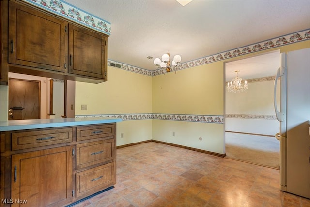 5200 Tanglewood Ave NE, Louisville, OH 44641 - kitchen featuring a chandelier, freestanding refrigerator, light stone finish floors, and light countertops