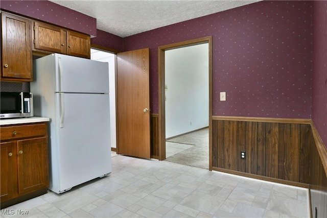 894 Pearson Cir Unit 3, Boardman, OH 44512 - kitchen featuring freestanding refrigerator, stainless steel microwave, wallpapered walls, a textured ceiling, and light countertops