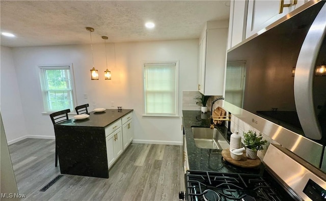 16721 Lomond Blvd, Shaker Heights, OH 44120 - kitchen with a textured ceiling, a peninsula, white cabinets, light wood finished floors, and dark countertops