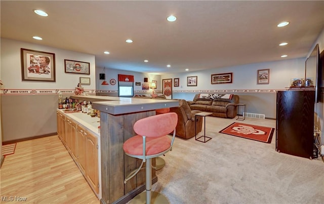 99 Mccook Ave, Carrollton, OH 44615 - kitchen featuring a peninsula, recessed lighting, light wood finished floors, a kitchen bar, and light countertops