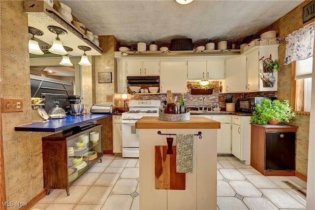 99 Mccook Ave, Carrollton, OH 44615 - kitchen featuring white range with gas cooktop, extractor fan, white cabinets, a center island, and light tile patterned floors