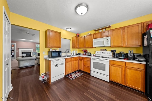 1446 Chesapeake Ave, Louisville, OH 44641 - kitchen featuring white appliances, light countertops, dark wood-style flooring, a ceiling fan, and a glass covered fireplace