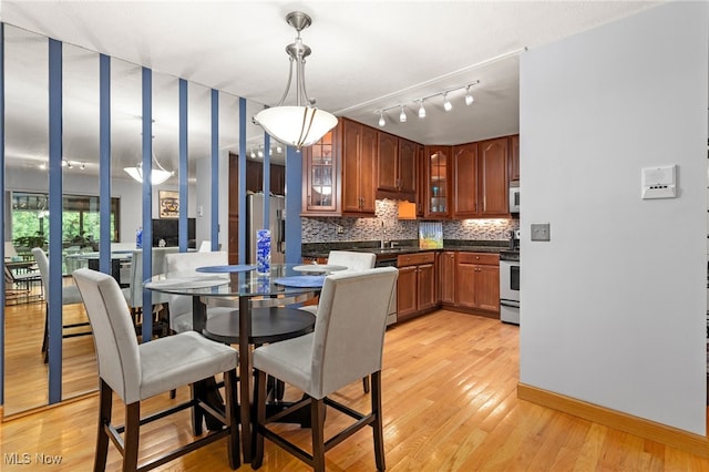 22936 Mastick Rd, Fairview Park, OH 44126 - kitchen featuring stainless steel appliances, dark countertops, backsplash, glass insert cabinets, and light wood-style floors