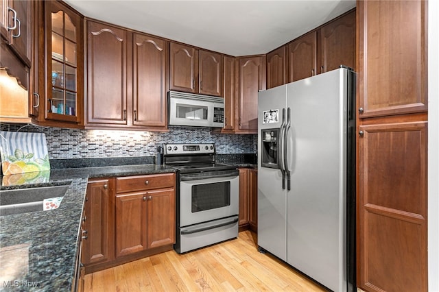 22936 Mastick Rd, Fairview Park, OH 44126 - kitchen with appliances with stainless steel finishes, light wood-style floors, glass insert cabinets, dark stone countertops, and tasteful backsplash