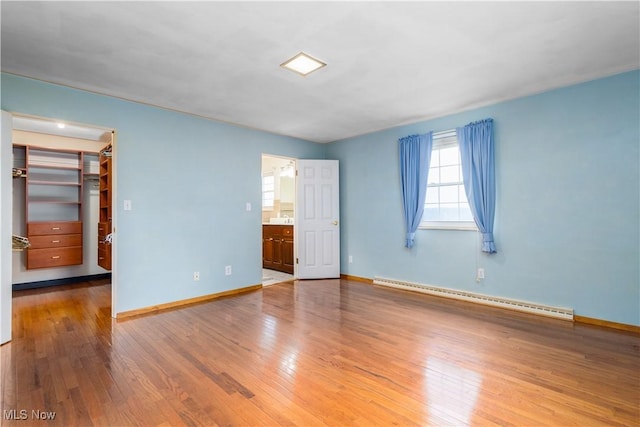 3945 Palisades Dr, Weirton, WV 26062 - unfurnished bedroom featuring a baseboard heating unit, a walk in closet, wood finished floors, and ensuite bath