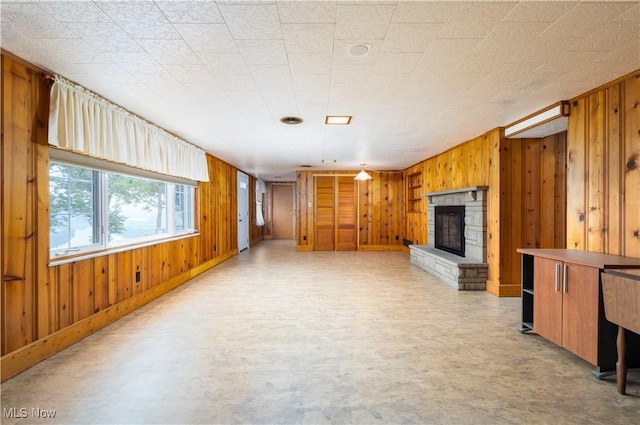 3945 Palisades Dr, Weirton, WV 26062 - unfurnished living room featuring wooden walls, a stone fireplace, and light floors