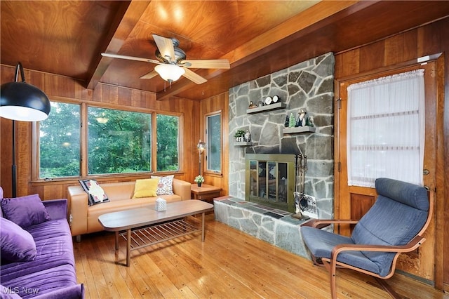 5552 Briarcliff Dr, Garfield Heights, OH 44125 - living room featuring a wooden ceiling with exposed beams, wooden walls, wood-type flooring, a stone fireplace, and a ceiling fan