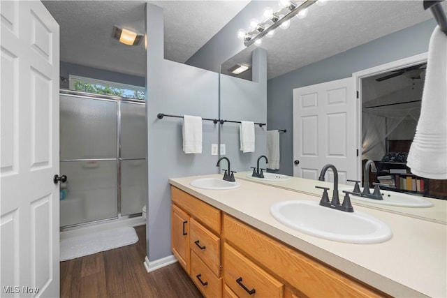 9034 Huxley Ln, Olmsted Twp, OH 44138 - full bathroom featuring double vanity, wood finished floors, an enclosed shower, and a textured ceiling
