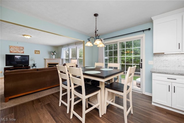 9034 Huxley Ln, Olmsted Twp, OH 44138 - dining space featuring a chandelier, dark wood finished floors, and a fireplace