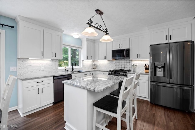 9034 Huxley Ln, Olmsted Twp, OH 44138 - kitchen featuring appliances with stainless steel finishes, white cabinets, dark wood-style floors, light stone countertops, and a textured ceiling