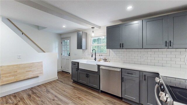 3187 Grenfall Rd, Norton, OH 44203 - kitchen with stainless steel dishwasher, range, backsplash, gray cabinets, and wood finished floors