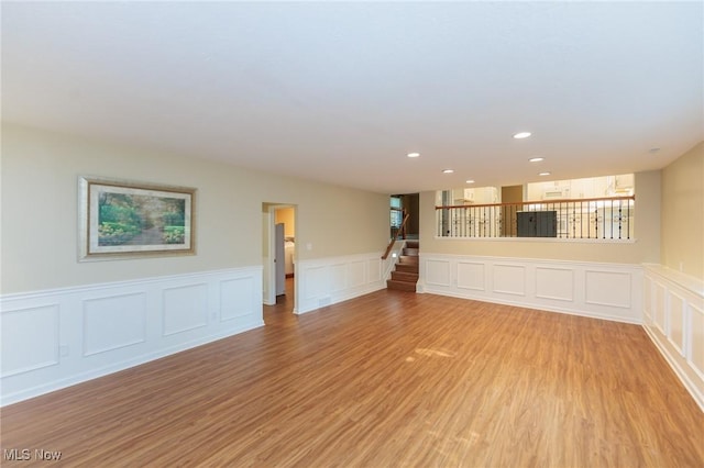 2271 Augusta Ct, Westlake, OH 44145 - unfurnished living room featuring wainscoting, a decorative wall, light wood finished floors, stairs, and recessed lighting
