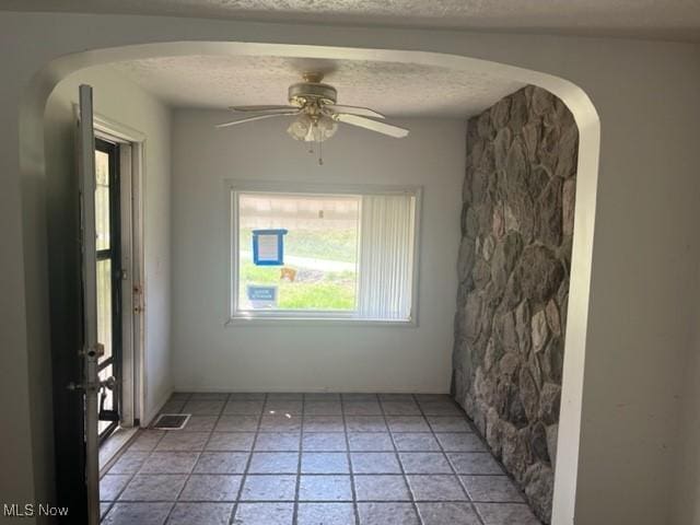 70610 Chermont Rd, Bridgeport, OH 43912 - unfurnished room featuring a ceiling fan, arched walkways, a textured ceiling, and light tile patterned floors