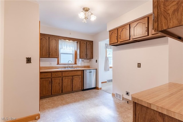 1403 Wexford Ave, Parma, OH 44134 - kitchen with dishwasher, brown cabinetry, light countertops, and a chandelier