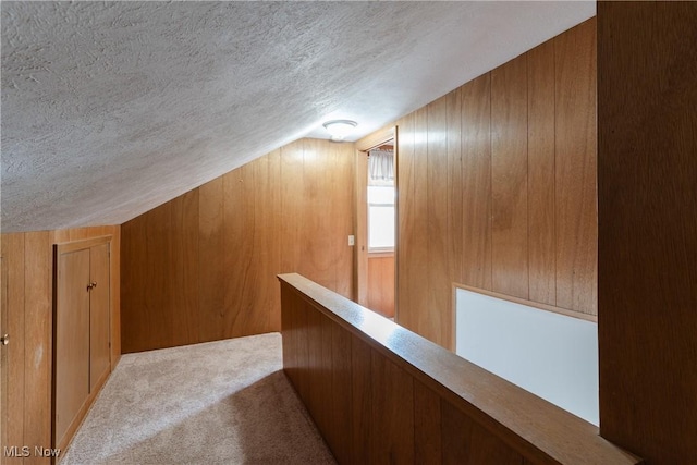 1403 Wexford Ave, Parma, OH 44134 - hall featuring a textured ceiling, carpet, lofted ceiling, wood walls, and an upstairs landing