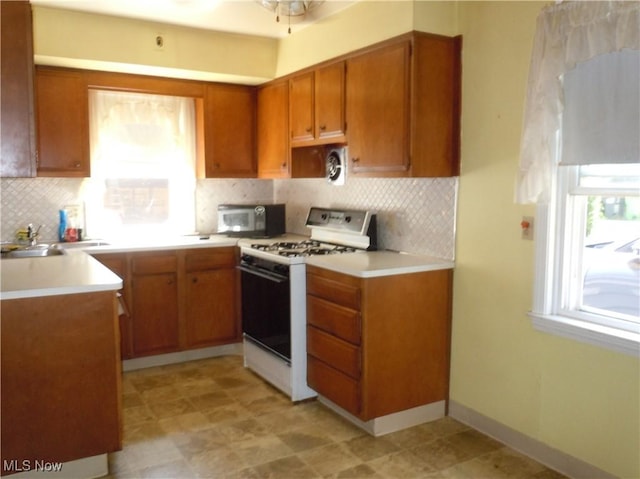 373 E 232nd St, Euclid, OH 44123 - kitchen with white gas stove, brown cabinets, healthy amount of natural light, and backsplash