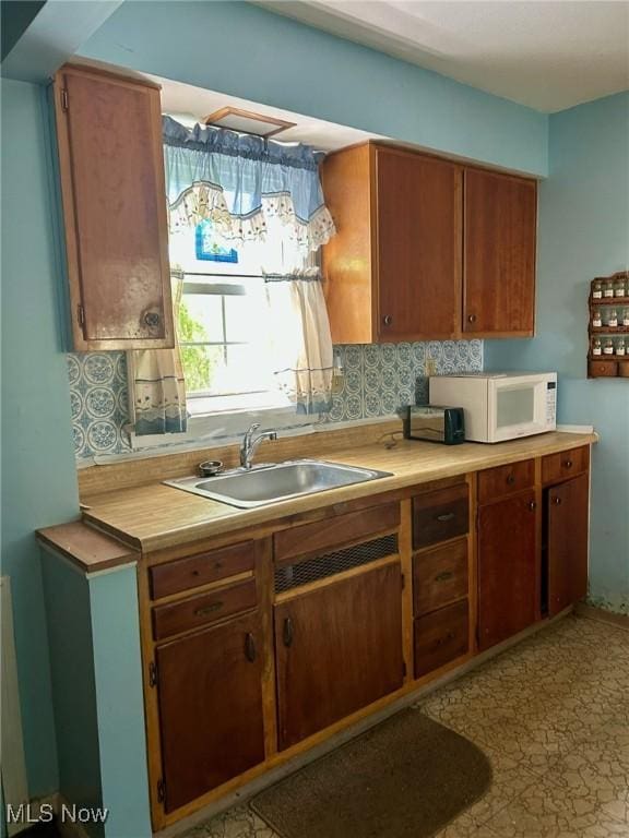 330 Inwood Blvd, Avon Lake, OH 44012 - kitchen with white microwave, decorative backsplash, light countertops, and brown cabinetry