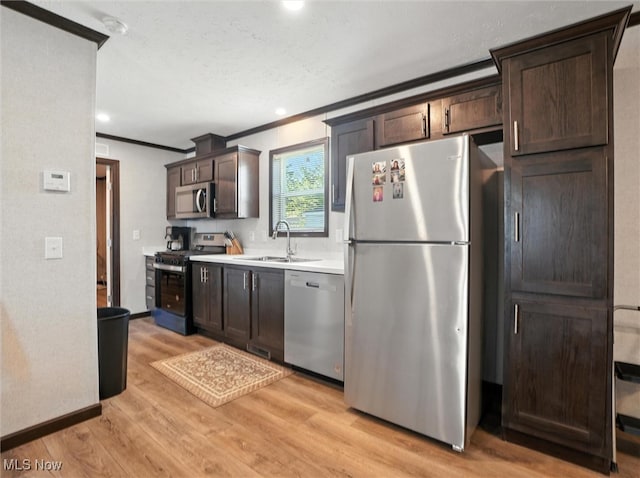 187 Garfield Ln, Jefferson, OH 44047 - kitchen featuring appliances with stainless steel finishes, ornamental molding, dark brown cabinets, light wood-style floors, and light countertops