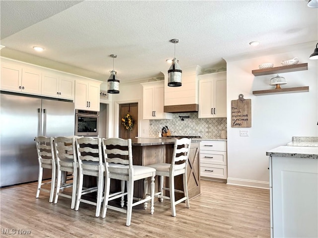 2710 E Hutton Rd, Wooster, OH 44691 - kitchen featuring stainless steel appliances, white cabinets, a kitchen island, decorative backsplash, and a breakfast bar area