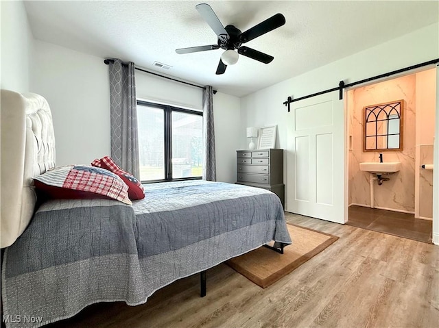 2710 E Hutton Rd, Wooster, OH 44691 - bedroom with a barn door, wood finished floors, ceiling fan, and a textured ceiling